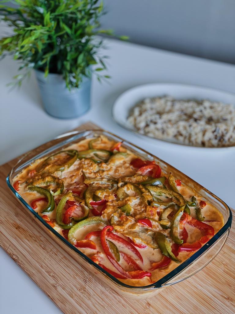 Rezeptbild Paprika Sahne Hähnchen vegan in Auflaufform daneben ein Teller Reis