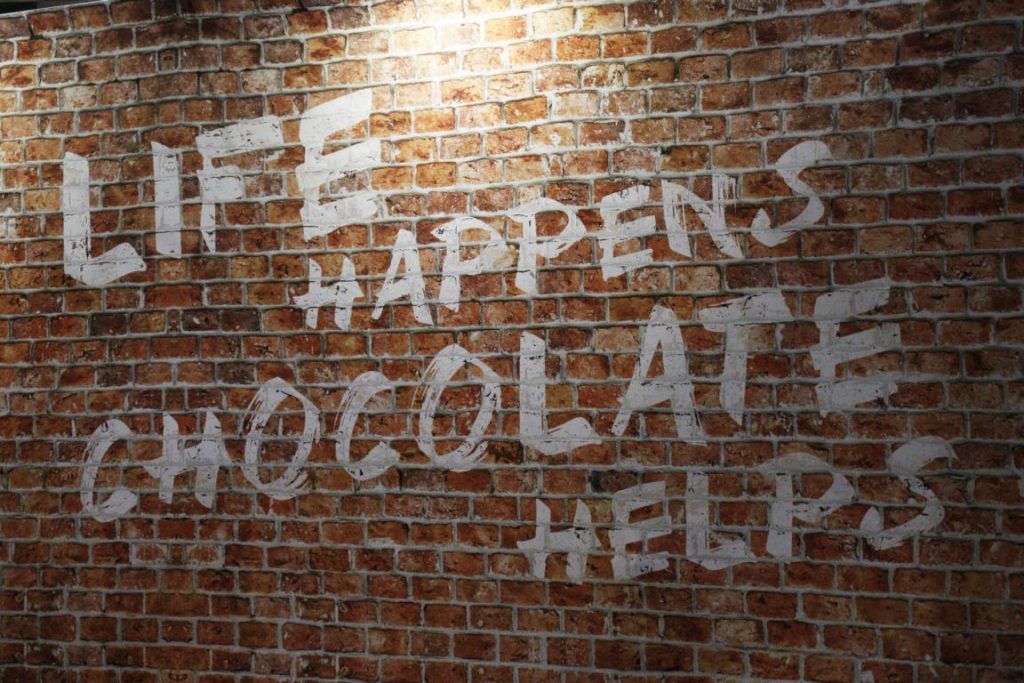 Backsteinwand mit "Life happens, Chocolate helps" Schriftzug