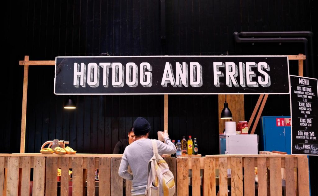 Besucher:in an Hotdog & Fried Stand