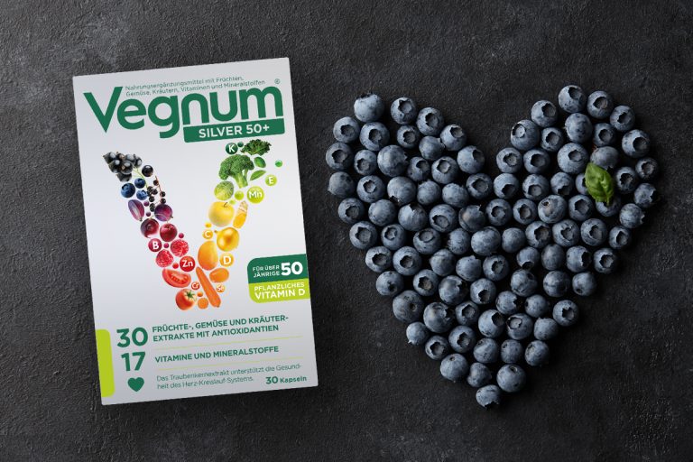 Verpackung von Veganem Nahrungsergänzungsmittel neben einem Herz aus Blaubeeren