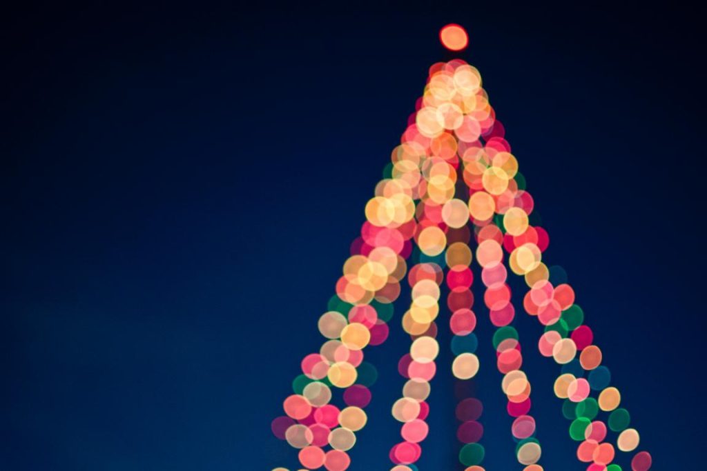 Symbolbild Weihnachtszeit: Lichterkette in Tannenbaumform unter dunklem Himmel